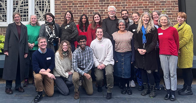 Members of the creative health group smile together wearing casual clothes.